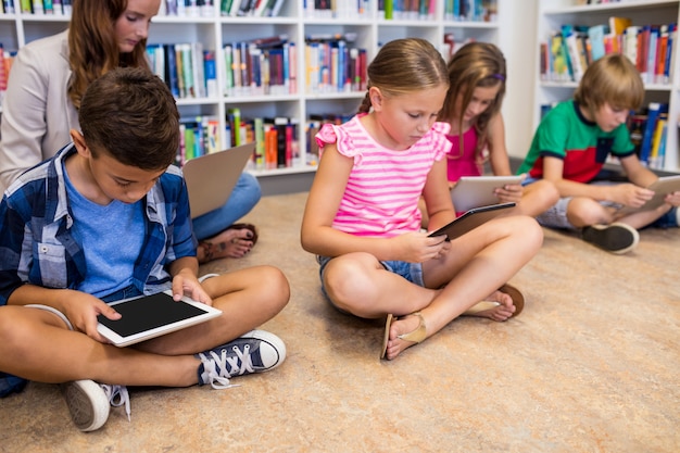 A group of students in a Spanish elementary school using tablets in a classroom, participating in a collaborative project focused on science, with one student pointing to a diagram of the solar system.