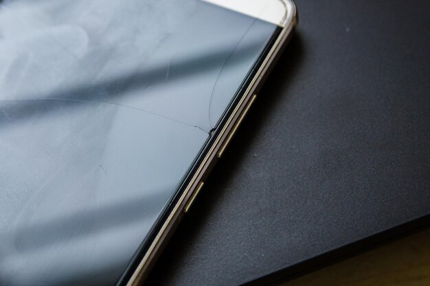 A close-up of a cracked smartphone screen displaying a phishing email attempting to steal banking credentials. The background shows blurred silhouettes of pedestrians walking in a busy urban street, symbolizing the vulnerability of mobile security in public spaces.