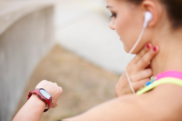 A close-up of a smartwatch displaying various health metrics such as heart rate, steps taken, and calories burned. The background is a blurred image of a person running