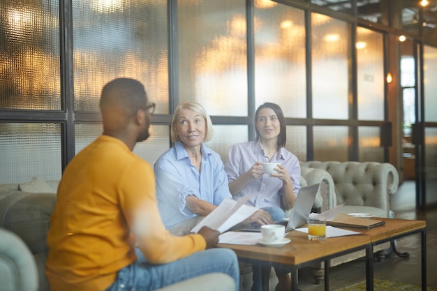 A group of diverse professionals sitting around a table in a bright meeting room, focused on a presentation about sustainable business practices. The participants are engaged in active listening and discussion, emphasizing a commitment to environmental responsibility and innovative solutions.