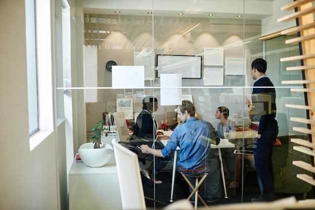 A photo of a modern coworking space in Singapore, filled with people from diverse backgrounds working on laptops. A whiteboard with diagrams related to AI algorithms is visible.