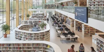 Interior moderno de biblioteca pública en España con personas leyendo y participando.